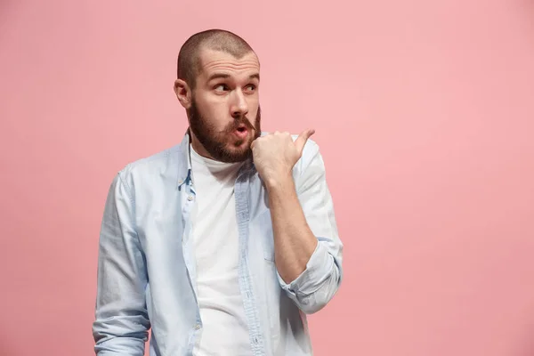 Der junge Mann flüstert ein Geheimnis hinter ihrer Hand über rosa Hintergrund — Stockfoto