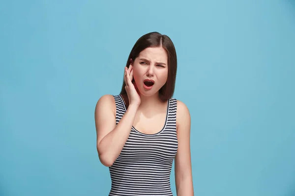 Il mal d'orecchio. La donna triste con mal di testa o dolore su uno sfondo blu studio . — Foto Stock