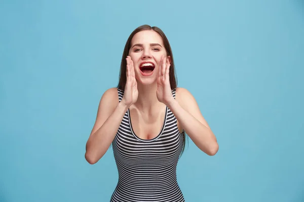 Geïsoleerd op blauwe jonge casual vrouw schreeuwen in studio — Stockfoto