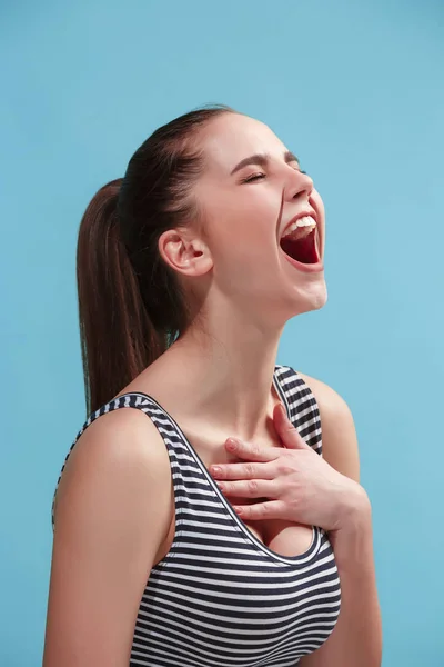 De gelukkige vrouw permanent en glimlachend tegen blauwe achtergrond. — Stockfoto