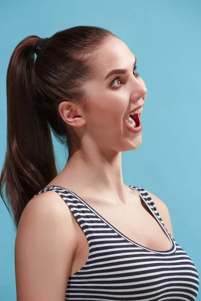 The young woman is looking crazy on the blue background. — Stock Photo, Image