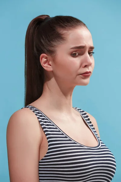 La giovane donna sembra triste sullo sfondo blu . — Foto Stock