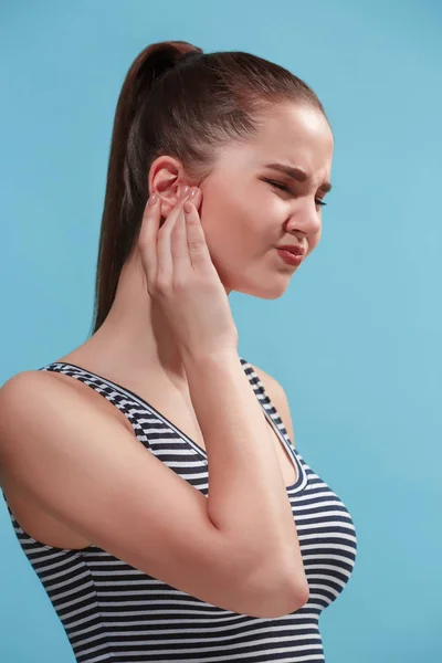 A dor de ouvido. A mulher triste com dor de cabeça ou dor em um fundo estúdio azul . — Fotografia de Stock
