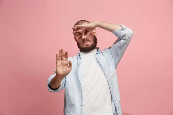 Junger Mann mit angeekeltem Gesichtsausdruck, der etwas abstößt, isoliert auf der rosa — Stockfoto
