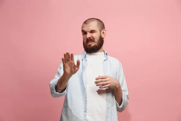 Junger Mann mit angeekeltem Gesichtsausdruck, der etwas abstößt, isoliert auf der rosa — Stockfoto