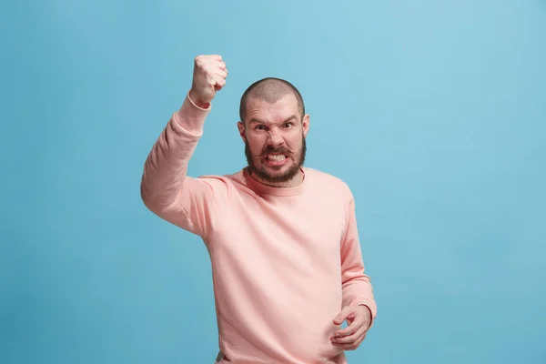 Nuori emotionaalinen vihainen mies huutaa vaaleanpunainen studio tausta — kuvapankkivalokuva