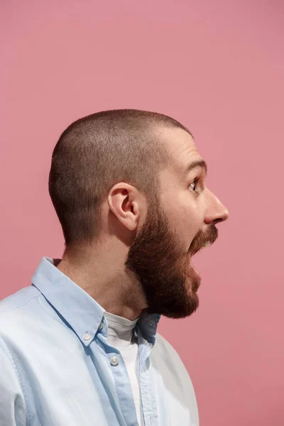 Den unge känslomässiga överraskande mannen skrek på rosa studio bakgrund — Stockfoto