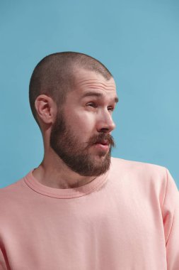 Mavi izole genç casual adam stüdyoda sıkıcı