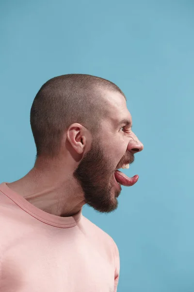 O jovem homem irritado emocional gritando no fundo do estúdio azul — Fotografia de Stock