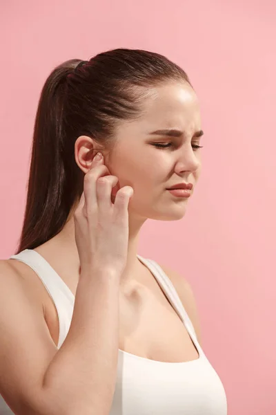 A dor de ouvido. A mulher triste com dor de cabeça ou dor em um fundo de estúdio rosa . — Fotografia de Stock
