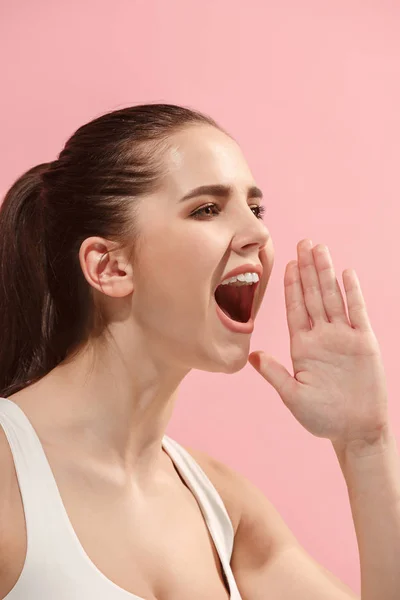 Geïsoleerd op roze jonge casual vrouw schreeuwen in studio — Stockfoto