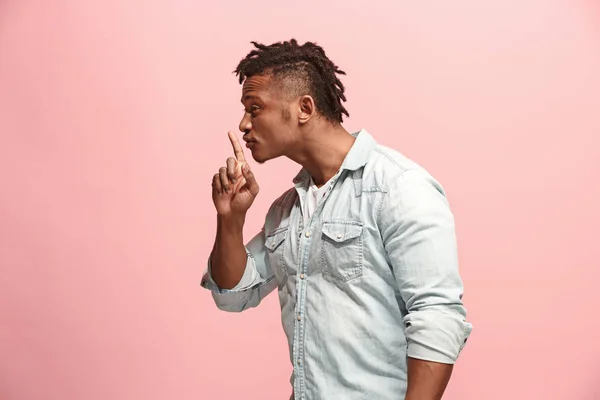 The young man whispering a secret behind her hand over pink background