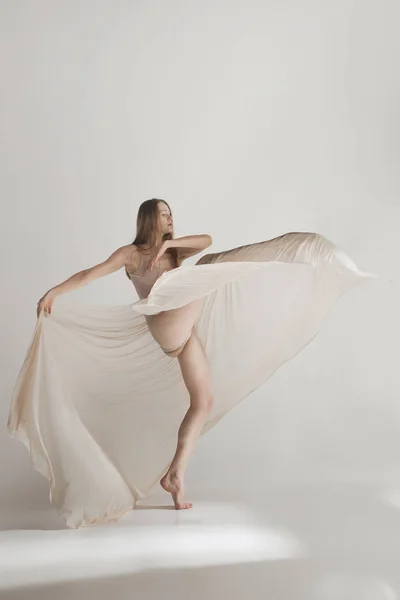 Młoda piękna tancerka beżowy strój kąpielowy taniec na szarym tle — Zdjęcie stockowe