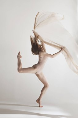 Genç güzel dansçı bej mayo gri arka plan üzerinde dans