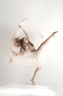 Genç güzel dansçı bej mayo gri arka plan üzerinde dans