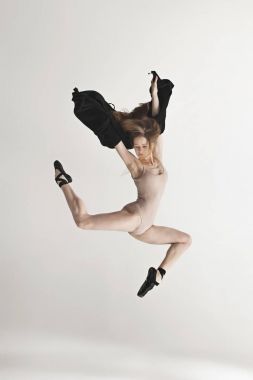 Genç güzel dansçı bej mayo gri arka plan üzerinde dans