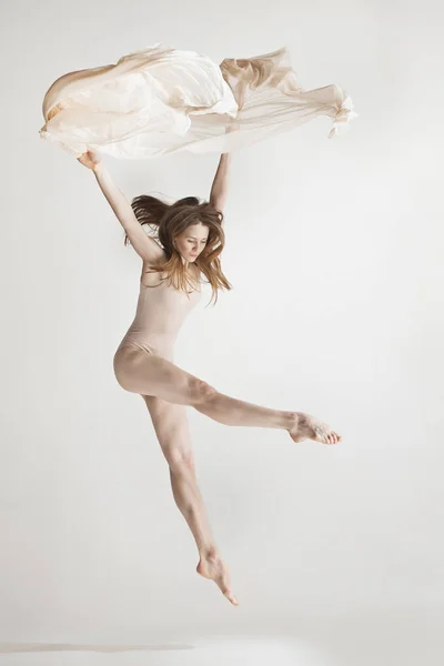 Joven hermosa bailarina en traje de baño beige bailando sobre fondo gris — Foto de Stock