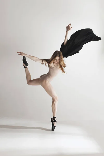 Giovane bella ballerina in costume da bagno beige che balla su sfondo grigio — Foto Stock