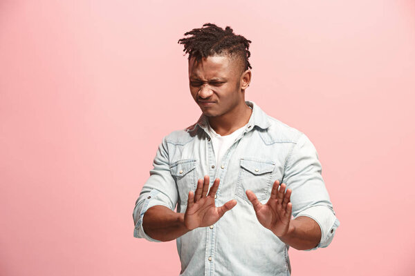 Young man with disgusted expression repulsing something, isolated on the pink