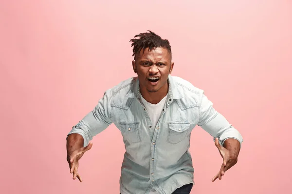Молодий емоційний розлючений афро-чоловік кричить на рожевому студійному фоні — стокове фото
