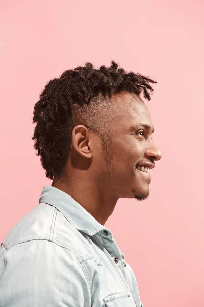 Szczęśliwy działalności człowieka afro-amerykański, stałego i uśmiechając się różowym tle. Widok profilu. — Zdjęcie stockowe