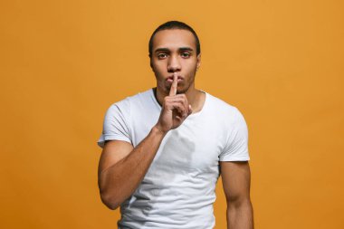 Turuncu arka plan üzerinde elini arkasındaki sır fısıldayan genç adam