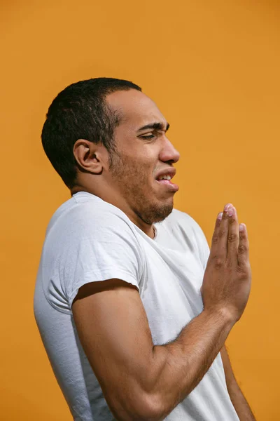 El hombre afroamericano repugnante se ve repugnantemente contra el fondo naranja —  Fotos de Stock