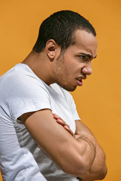 Arga Afro-American mannen tittar allvarligt mot orange bakgrund — Stockfoto