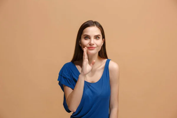 Die junge Frau flüstert ein Geheimnis hinter ihrer Hand über pastellfarbenem Hintergrund — Stockfoto