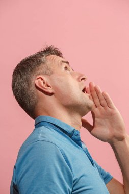 Pembe arka plan üzerinde elini arkasındaki sır fısıldayan genç adam