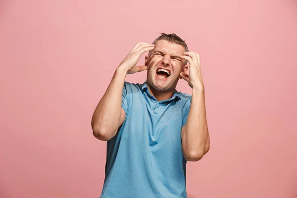 Il giovane uomo arrabbiato emotivo urla su sfondo rosa studio — Foto Stock