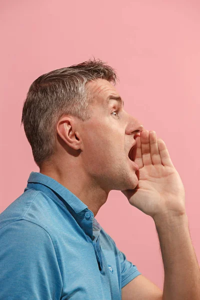 Ізольовані на рожевий молодий випадковий чоловік кричить в студії — стокове фото