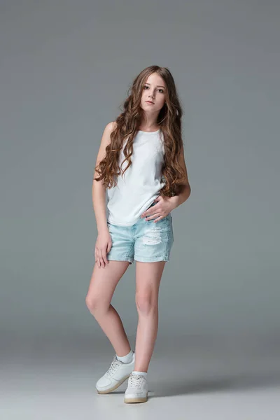 Longitud completa de la joven delgada chica femenina en pantalones cortos de mezclilla sobre fondo gris —  Fotos de Stock