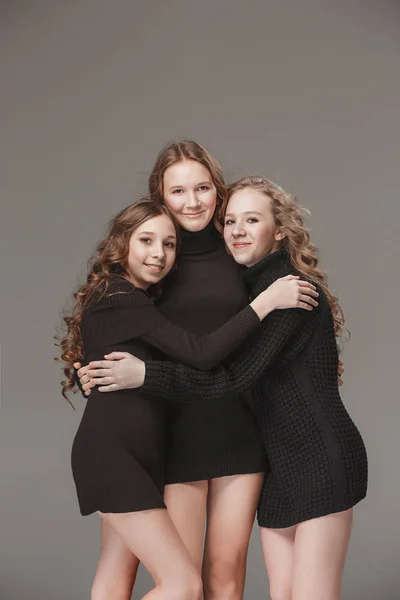 The fashion girls standing together and looking at camera over gray studio background — Stock Photo, Image