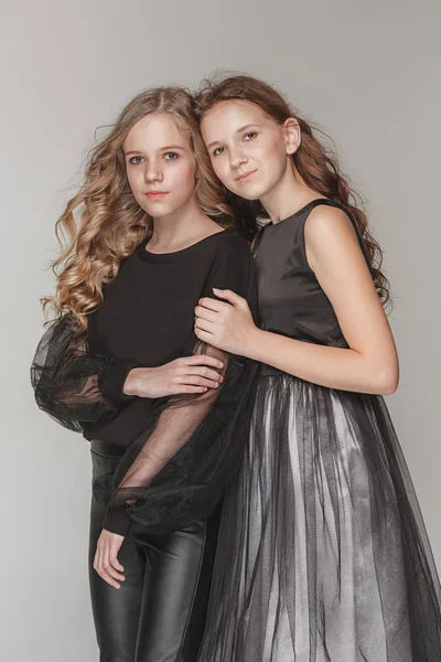 Le ragazze di moda in piedi insieme e guardando la fotocamera su sfondo grigio studio — Foto Stock