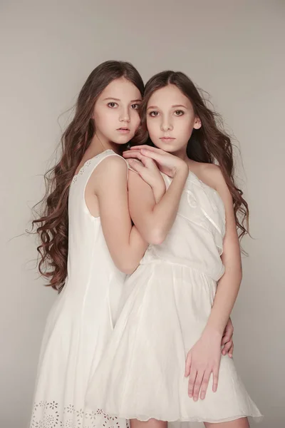Dziewczyny moda razem stojąc i patrząc na kamery przez studio szary tło — Zdjęcie stockowe