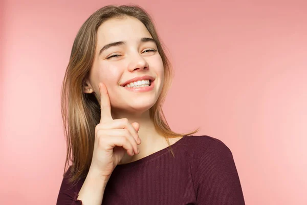 Mujer sonriendo con una sonrisa perfecta y dientes blancos en el fondo del estudio rosa y mirando a la cámara — Foto de Stock