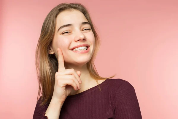 Femme souriant avec un sourire parfait et des dents blanches sur le fond du studio rose et regardant la caméra — Photo