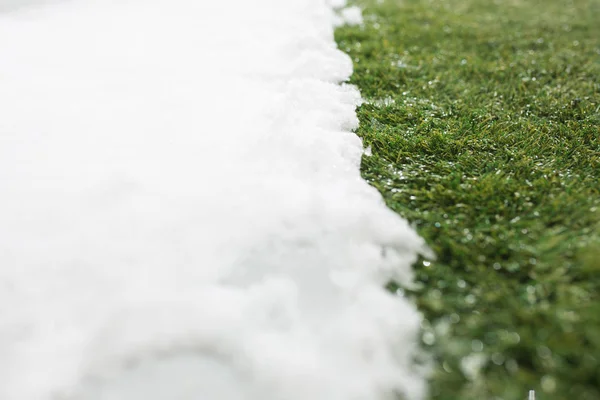 Incontro neve su erba verde da vicino - tra inverno e primavera concetto di sfondo — Foto Stock