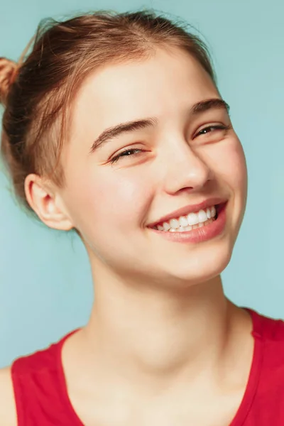 Mujer sonriendo con una sonrisa perfecta en el fondo azul del estudio y mirando a la cámara — Foto de Stock