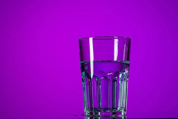 The water in glass on lilac background — Stock Photo, Image