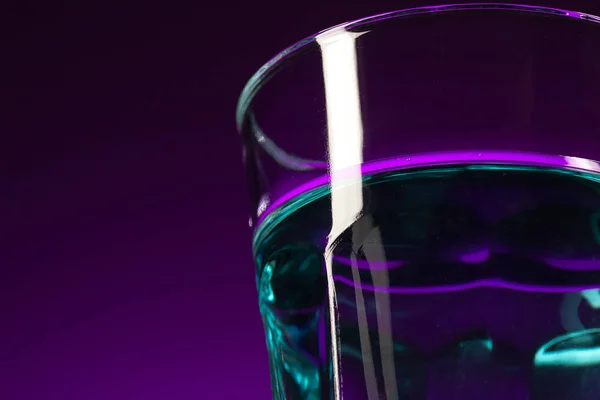 Das Wasser im Glas auf fliederfarbenem Hintergrund — Stockfoto