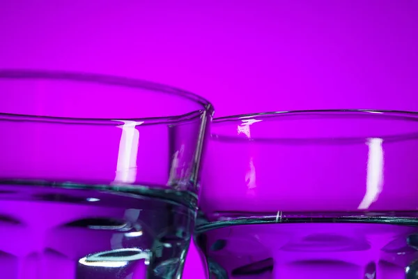 Das Wasser in zwei Glasscheiben auf fliederfarbenem Hintergrund — Stockfoto