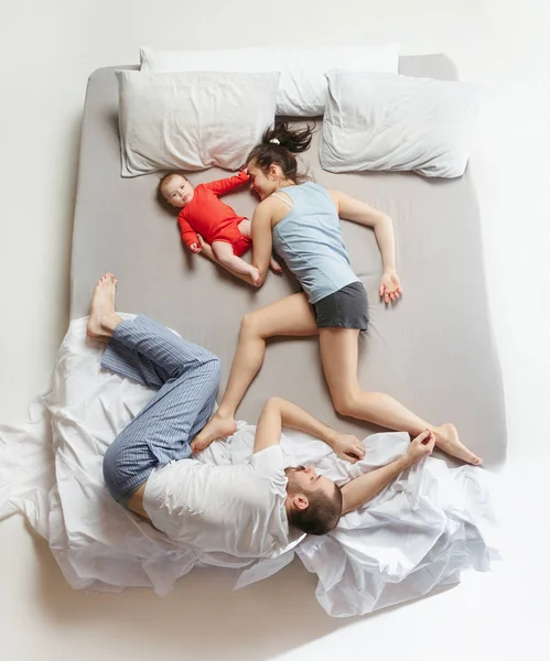 Top view of happy family with one newborn child in bedroom.