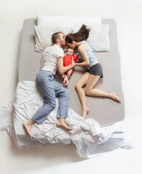 Top view of happy family with one newborn child in bedroom.