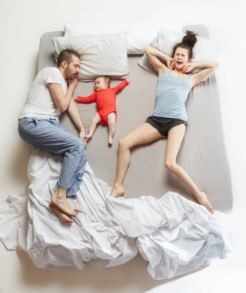 Top view of happy family with one newborn child in bedroom.