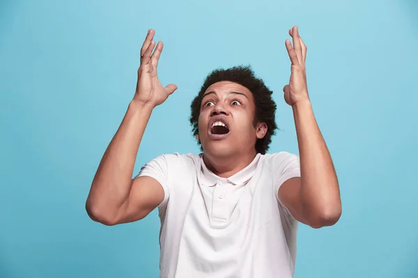 Молодий емоційно розлючений чоловік кричить на синьому студійному фоні — стокове фото