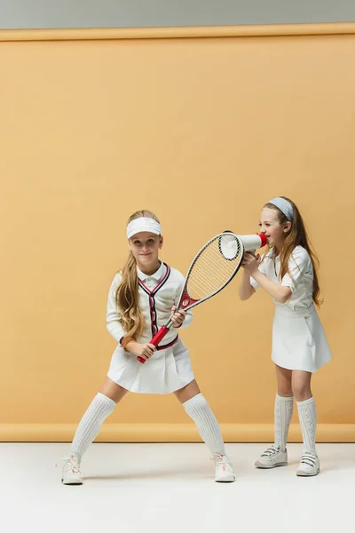 Portrét dvou dívek jako tenistů držící tenisovou raketu. Studio záběr. — Stock fotografie