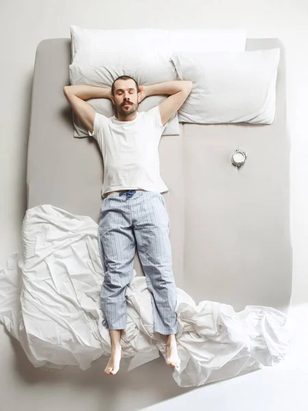 Vista superior de la foto de un hombre joven durmiendo en una gran cama blanca —  Fotos de Stock