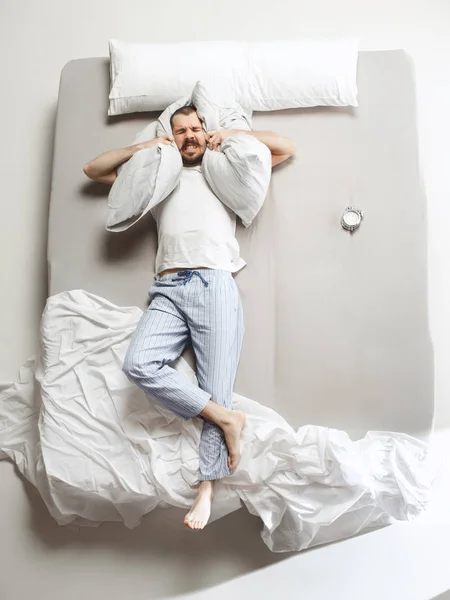 Ovanifrån foto av ung man sover i en stor vit säng — Stockfoto